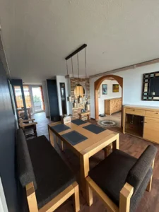 Essbereich mit Holztisch, Bänken, Stühlen, Pendelleuchte, Steinwand, Spiegel und Sideboard.
