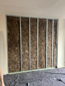 Wand mit Metallständern und Dämmmaterial, Boden mit Schutzvlies bedeckt.