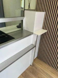 Moderner Empfangsbereich mit Holzverkleidung, weißem Tresen und Vase auf Holzfußboden.