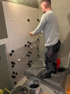 Person fließt Wand mit Abstandshaltern auf Plane, Werkzeuge und Materialien verteilt.